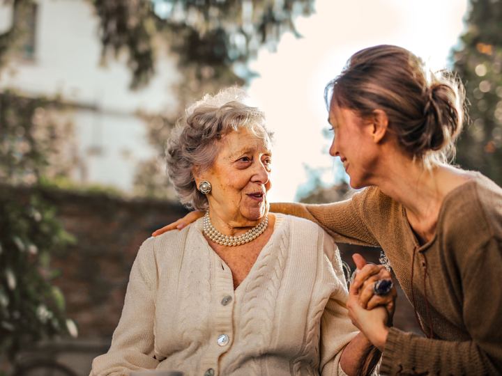 Adult daughter smiling with her senior mother, holding her hand