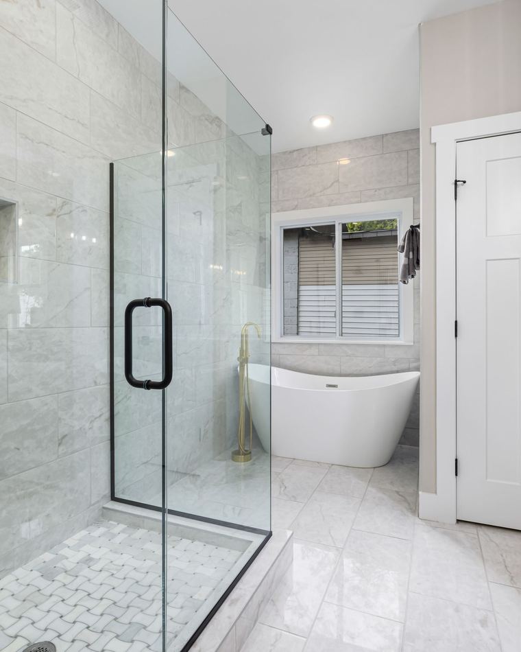 Bathroom remodel idea: walk-in shower with a frameless glass enclosure, tiled niche, and freestanding tub