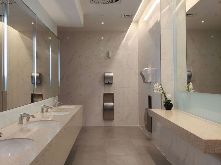 Modern commercial restroom with a long counter, a row of sinks, and wall mirrors