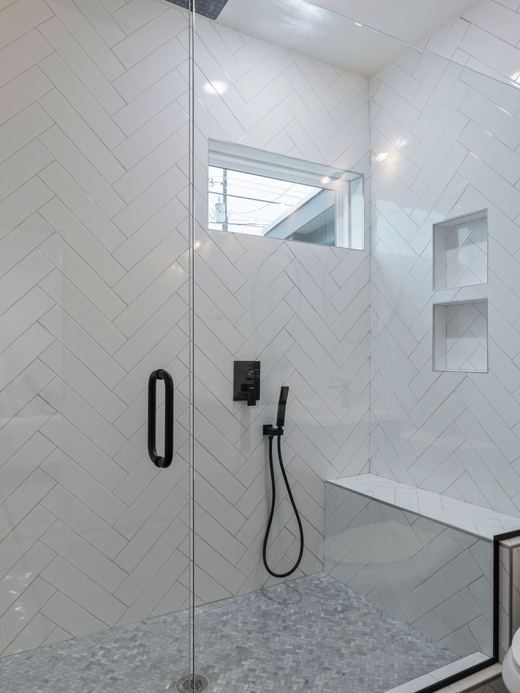 Walk-in shower idea: white herringbone tile, a built-in bench, and black fixtures