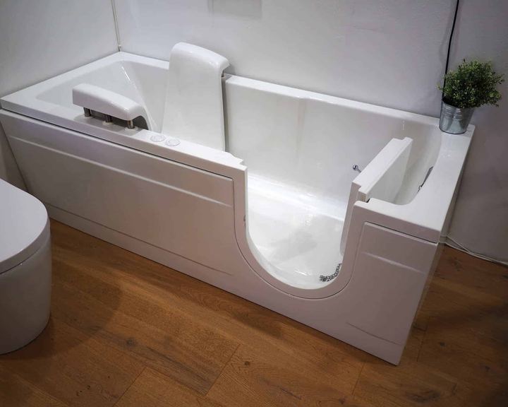 Walk-in tub with an open door and built-in seat in a bathroom with wood flooring